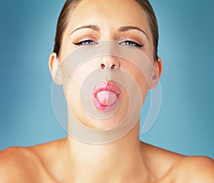 Sometimes we all need a little silliness. Studio portrait of a beautiful young woman sticking her tongue out against a