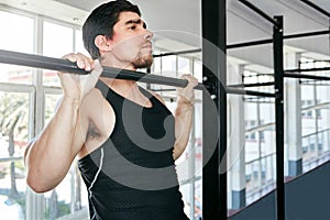 Sometimes the basic exercises are best. a young man doing pull ups in a gym.