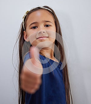 Sometimes we just need a little encouragement. Shot of an adorable little girl showing thumbs up while posing against a