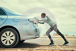 Sometimes youve gotta get out and push. Full length shot of a young man pushing his car along the road after breaking