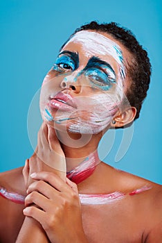 Sometimes youve just gotta stand out. Studio portrait of a beautiful young woman covered in face paint posing against a