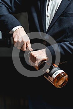 Sommelier in a dark blue jacket opens a bottle of rose wine