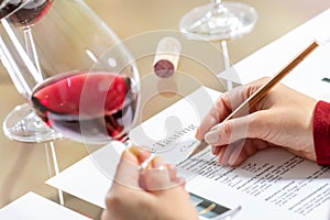 Sommelier evaluating red wine taking notes at table