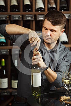 Sommelier opening white wine bottle with corckcrew