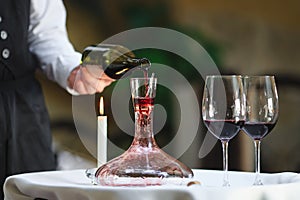 A sommelier pouring red wine into decanter