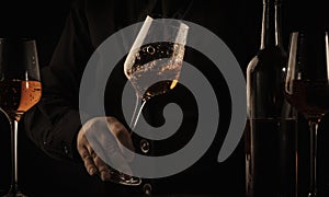 Sommelier pouring rose wine into glass at wine tasting in winery, bar or restaurant. Black toned image