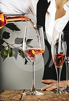 Sommelier pouring rose wine into glass at wine tasting in winery, bar or restaurant. White background photo