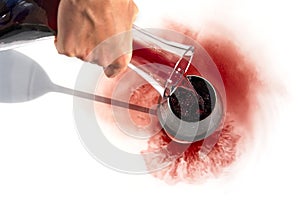 Sommelier pours red wine from decanter to wineglass on white background.