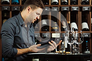 Sommelier reading label of wine bottle in hands