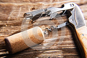 Sommelier`s knife with a wine cork on an old wooden table. Close-up. Selective focus. Space for text