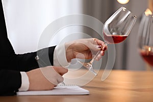 Sommelier tasting wine at table indoors, closeup