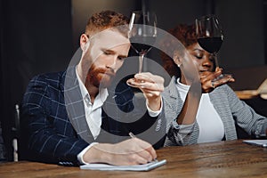 Sommeliers man and woman tasting red wine and making notes at degustation notepad