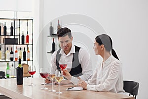 Sommeliers tasting different sorts of wine at table indoors