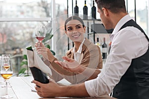 Sommeliers tasting different sorts of wine at table indoors