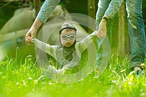 Son baby in pilot helmet holding hands with mother