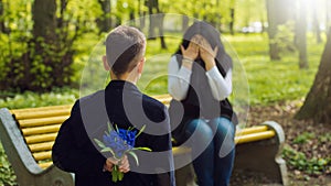 Son with bunch of beautiful flowers behind back preparing nice surprise for his mother.