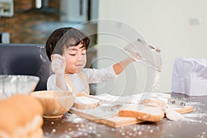 Son cooking food. Preparing an ingredient with flour and bread. Kid daily lifestyle at home. Asian family