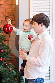 Son and dad decorating the christmas tree at home in the living room