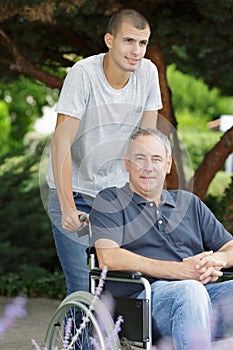 Son and dad sitting in wheelchair oudtoors photo