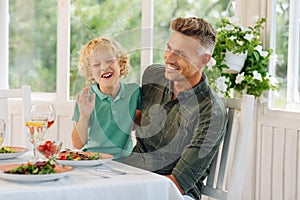 Son and daddy laughing while eating lunch outside together