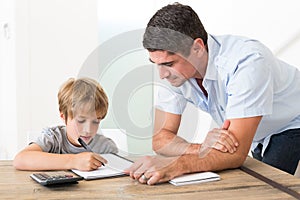 Son doing homework while father standing by