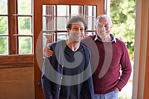 Son, elderly father and portrait in home by front door with hug, smile and bonding with connection. Men, senior dad and