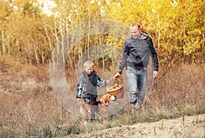 Son with father carry full basket of mushrooms in autumn forest