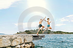 Son with Father having a fun on a merry vacation days on Adriatic sea coast. They dressed swimming trunks jumping to the waives