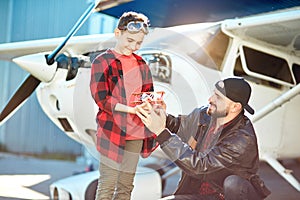 Son and father holding toy plane, enjoying aeromodelling hobby