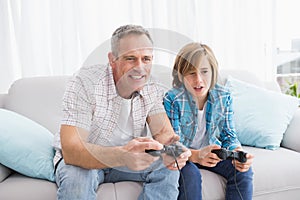 Son and father playing video games together on the couch