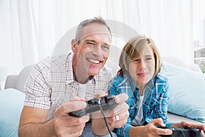 Son and father playing video games together on the couch
