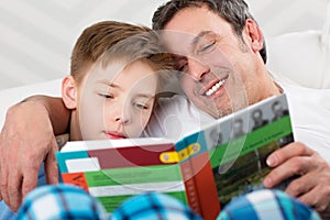 Son and father reading book together