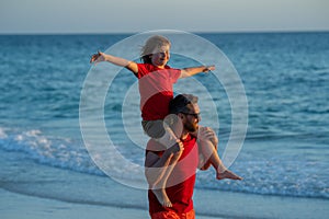 Son on fathers shoulders piggyback ride. Father and son walking together on the beach. Fatherhood family concept. Travel