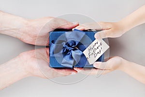 Son gives daddy present or gift box with tag on Happy fathers day. Holiday concept top view.