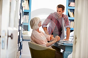 Son Giving Senior Parent Financial Advice In Home Office