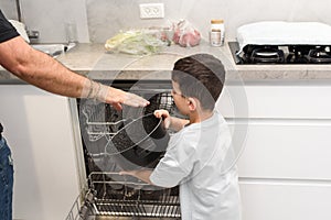 Son helping father with the dishwasher. Chores concept.