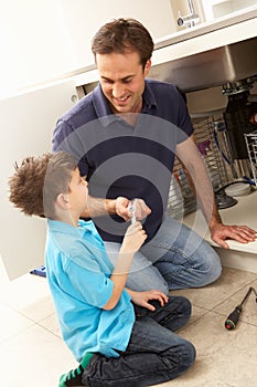 Son Helping Father To Mend Sink