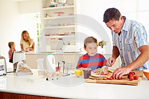 Son Helping Father To Prepare Family Breakfast In Kitchen