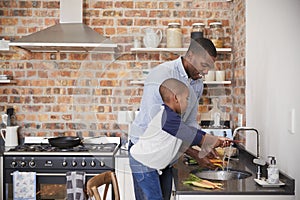 Son Helping Father To Prepare Vegetables For Meal In Kitchen