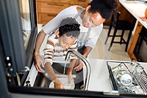 Son is helping mother in the Kitchen, Washing Dishes