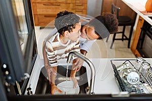 Son is helping mother in the Kitchen, Washing Dishes