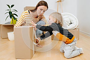 Son helping mother to pack, sealing box with scotch tape. they are moving out