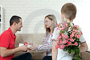 Son hiding bouquet to surprise mommy on mother`s day. Woman, man