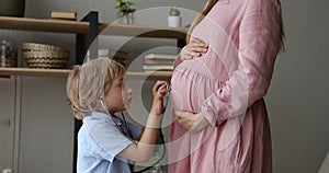 Son holds stethoscope listen heartbeat caring of his unborn sibling