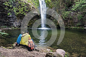 Son hugging dad looking water waterfall, happy together. Family vacancy, child and father love. Back view. Father`s day