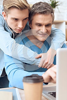 Son hugs mom while dad works at the computer.