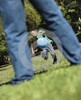 Son kicking ball to dad.