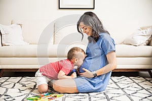 Son Kissing Abdomen Of Pregnant Mom In Living Room