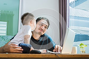 Son kissing his father while using internet. People and Lifestyles concept. Technology and Happy family theme. Single dad theme