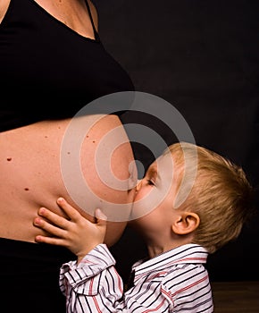 Son kissing pregnant belly